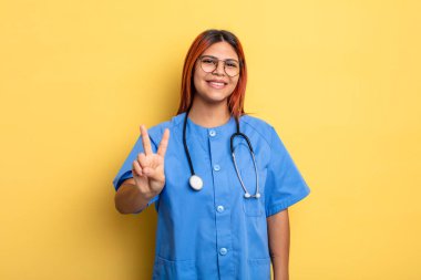 İspanyol kadın gülümsüyor ve arkadaş canlısı görünüyor, iki numarayı gösteriyor. hemşire konsepti