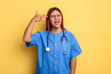 İspanyol kadın mutsuz ve stresli görünüyor, intihar jesti silah işareti yapıyor. hemşire konsepti