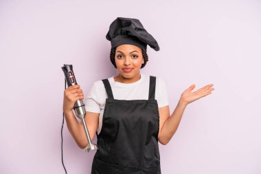 afro black woman feeling puzzled and confused and doubting. chef with hand blender