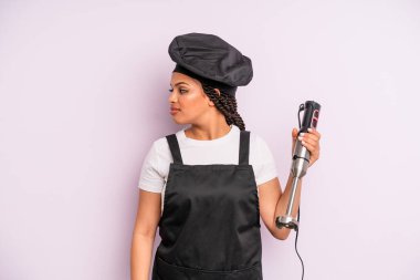 afro black woman on profile view thinking, imagining or daydreaming. chef with hand blender