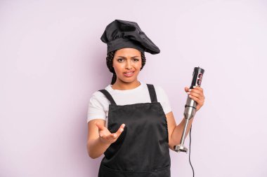 afro black woman looking angry, annoyed and frustrated. chef with hand blender
