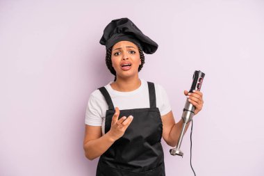 afro black woman looking desperate, frustrated and stressed. chef with hand blender