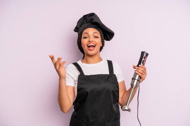afro black woman feeling happy, surprised realizing a solution or idea. chef with hand blender