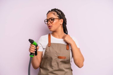 afro black woman feeling stressed, anxious, tired and frustrated. gardener hose concept