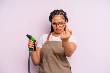 afro black woman feeling angry, annoyed, rebellious and aggressive. gardener hose concept