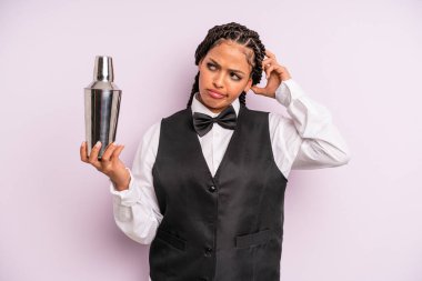 afro black woman smiling happily and daydreaming or doubting. waiter with a cocktail