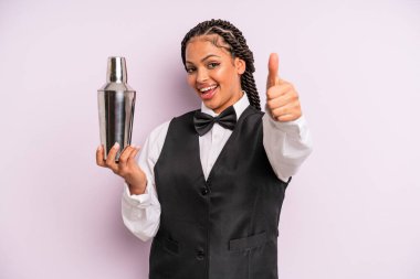 afro black woman feeling proud,smiling positively with thumbs up. waiter with a cocktail