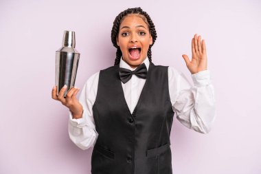 afro black woman feeling happy and astonished at something unbelievable. waiter with a cocktail