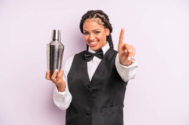 afro black woman smiling and looking friendly, showing number one. waiter with a cocktail