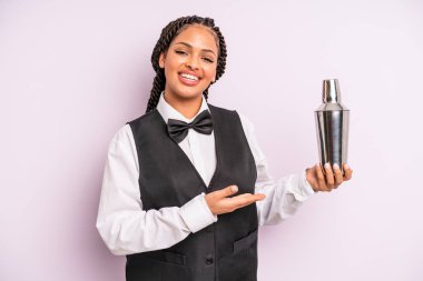 afro black woman smiling cheerfully, feeling happy and showing a concept. waiter with a cocktail