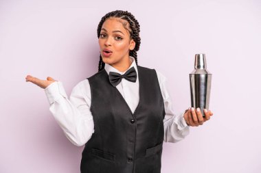 afro black woman looking surprised and shocked, with jaw dropped holding an object. waiter with a cocktail