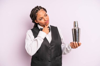 afro black woman thinking, feeling doubtful and confused. waiter with a cocktail