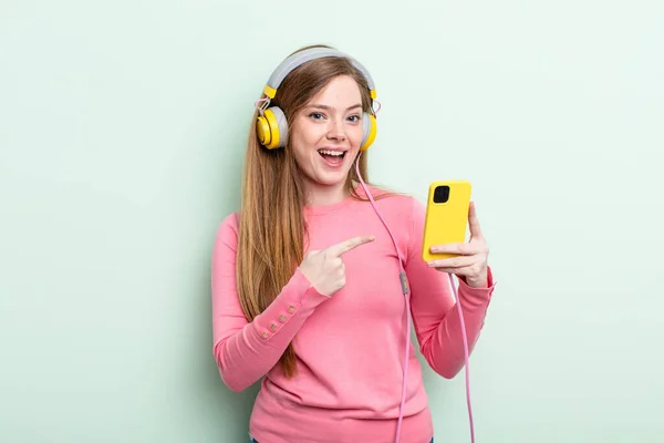 Redhair Woman Looking Excited Surprised Pointing Side Headphones Smartphone Concept — Stock Photo, Image