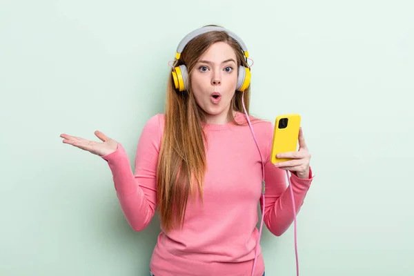 Redhair Woman Looking Surprised Shocked Jaw Dropped Holding Object Headphones — Stock Photo, Image