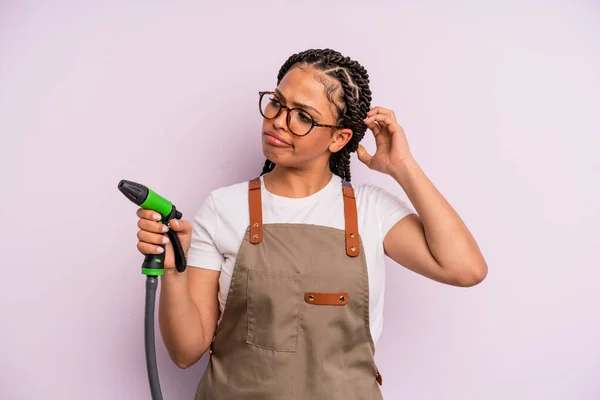 Afro Black Woman Feeling Puzzled Confused Scratching Head Gardener Hose – stockfoto