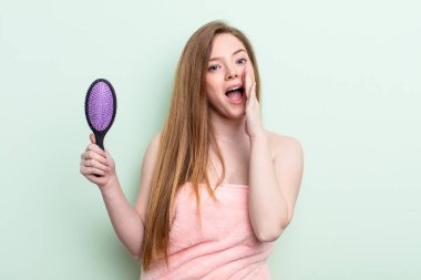 Kızıl saçlı kadın kendini mutlu hissediyor, elleri ağzının kenarında bağırıyor. saç tarağı konsepti