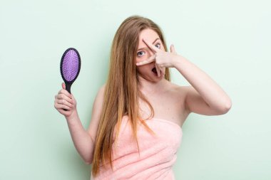 Kızıl saçlı kadın şok olmuş, korkmuş ya da dehşete düşmüş gibi görünüyor, yüzünü eliyle kapatıyor. saç tarağı konsepti