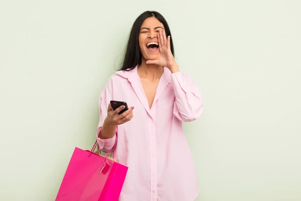 若いかなりヒスパニック系の女性は 手を口の横に大きな声を出す幸せを感じている ショッピングバッグのコンセプト — ストック写真