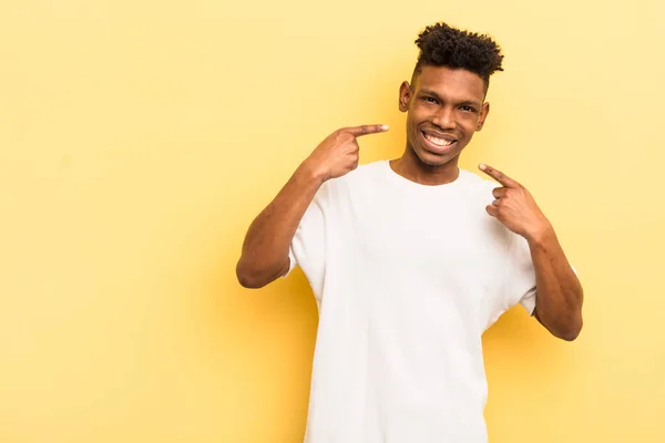 Preto Afro Jovem Sorrindo Confiantemente Apontando Para Próprio Sorriso Largo — Fotografia de Stock