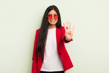 Genç, güzel İspanyol kadın gülümsüyor ve arkadaş canlısı görünüyor, dört numarayı gösteriyor. İş kadını kavramı
