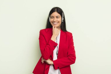 Mutlu, kendine güvenen, elleri çenesinde gülümseyen genç, güzel İspanyol bir kadın. telemarteker concpet