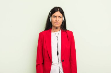 Genç, güzel, İspanyol bir kadın üzgün, üzgün ya da kızgın hissedip yan tarafa bakıyor. telemarteker concpet