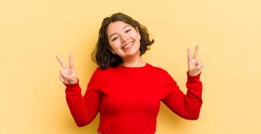 Güzel İspanyol kadın gülümsüyor ve mutlu görünüyor, arkadaş canlısı ve tatmin olmuş, zafer veya barış simgesi.