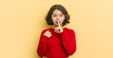 Güzel İspanyol bir kadın ciddi görünüyor ve parmaklarını dudaklarına bastırıp sessizlik ya da sessizlik talep ediyor, sır saklıyor.