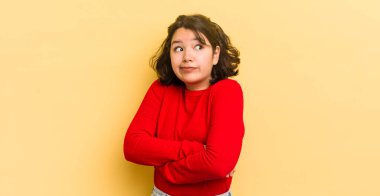 Güzel İspanyol bir kadın omuz silkiyor, kafası karışık ve emin değil, kolları bağlı ve şaşkın görünüyor.