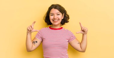 Güzel, İspanyol bir kadın kendi gülüşünü çiziyor, iki eliyle, olumlu ve mutlu görünüyor, sağIık kavramı.