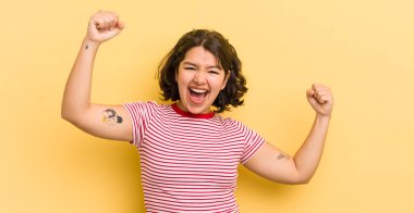 Güzel İspanyol kadın muzaffer bir şekilde bağırıyor, heyecanlı, mutlu ve şaşırmış görünüyor, kutlama yapıyor.