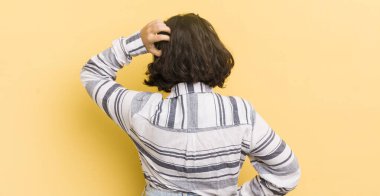 Güzel İspanyol bir kadın bilgisiz ve kafası karışık, bir çözüm düşünüyor, eli kalçasında, diğeri kafasında, dikiz aynasından.