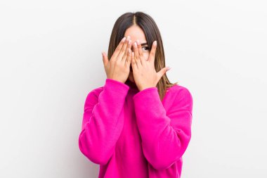 Güzel İspanyol kadın elleriyle yüzünü kapatıyor, parmaklarının arasından şaşkın bir ifadeyle yan tarafa bakıyor.