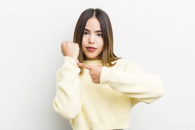 Güzel İspanyol bir kadın sabırsız ve kızgın görünüyor, saati gösteriyor, dakiklik istiyor, zamanında gelmek istiyor.