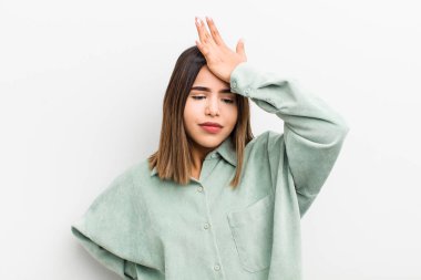 pretty hispanic woman raising palm to forehead thinking oops, after making a stupid mistake or remembering, feeling dumb