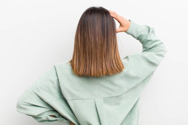 Güzel İspanyol bir kadın bilgisiz ve kafası karışık, bir çözüm düşünüyor, eli kalçasında, diğeri kafasında, dikiz aynasından.