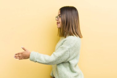 Güzel İspanyol kadın gülümsüyor, seni selamlıyor ve başarılı bir anlaşma için el sıkışmayı teklif ediyor.