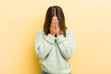 Güzel İspanyol bir kadın üzgün, hayal kırıklığına uğramış, gergin ve depresif, iki eliyle yüzünü kaplayan, ağlayan
