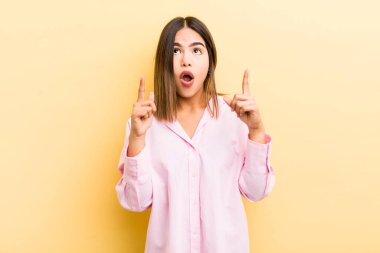 Güzel İspanyol kadın şaşırmış, şaşırmış ve ağzı açık görünüyor, iki eliyle boşluğu kopyalamak için yukarı bakıyor.