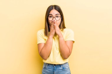 Güzel İspanyol bir kadın mutlu ve heyecanlı, şaşırmış ve hayrete düşmüş elleriyle ağzını kapatmış, tatlı bir ifadeyle kıkırıyor.