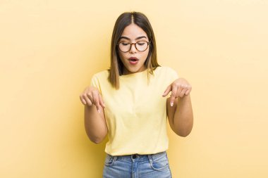 Güzel, ağzı açık, iki eliyle aşağıya bakan, şaşkın, şaşkın ve şaşırmış görünen İspanyol bir kadın.