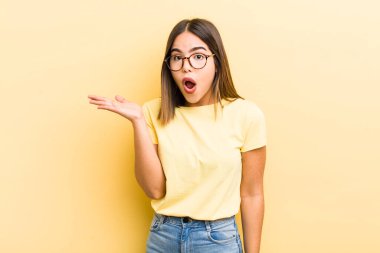 Güzel İspanyol kadın şaşırmış ve şok olmuş görünüyor, çenesi düşmüş, bir objeyi elinde açık bir elle tutuyor.