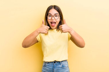 Güzel İspanyol kadın gülümsüyor mutlu, pozitif, kendine güvenen ve başarılı, iki başparmağı da havada.