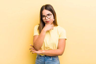 Güzel İspanyol bir kadın ciddi, düşünceli ve güvensiz görünüyor, bir kolu çapraz ve çene üzerinde, seçenekleri tartıyor