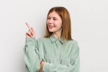 Kızıl saçlı güzel kadın mutlu bir şekilde gülümsüyor ve yan bakıyor, merak ediyor, düşünüyor ya da bir fikri var.