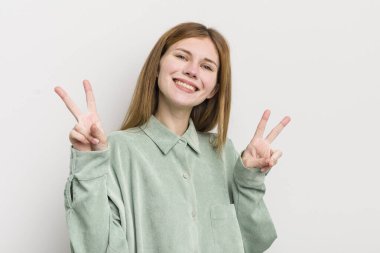 kızıl saçlı güzel kadın gülümsüyor ve mutlu görünüyor, arkadaş canlısı ve memnun, işaret eden zafer ya da huzur iki elinle