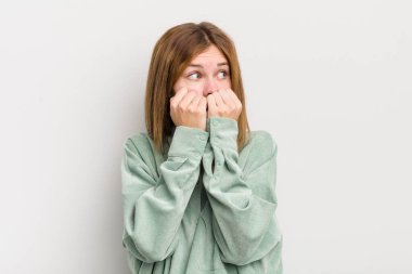 kızıl saçlı güzel kadın endişeli, stresli ve korkmuş görünüyor, tırnaklarını yiyor ve yanal fotokopi alanı arıyor.