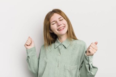 kızıl saçlı güzel kadın gülümsüyor, kaygısız hissediyor, rahat ve mutlu, dans ediyor ve müzik dinliyor, bir partide eğleniyor.