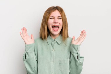 Kızıl saçlı güzel bir kadın mutlu, heyecanlı, şaşırmış ya da şok olmuş, gülümseyen ve hayrete düşmüş.