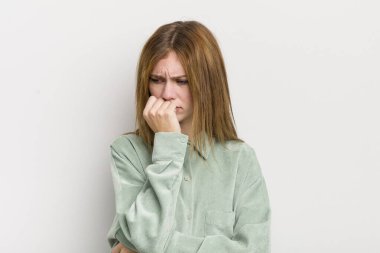 Kızıl saçlı güzel bir kadın ciddi, düşünceli ve endişeli, elleri çenesine bastırılmış, yan bakıyor.